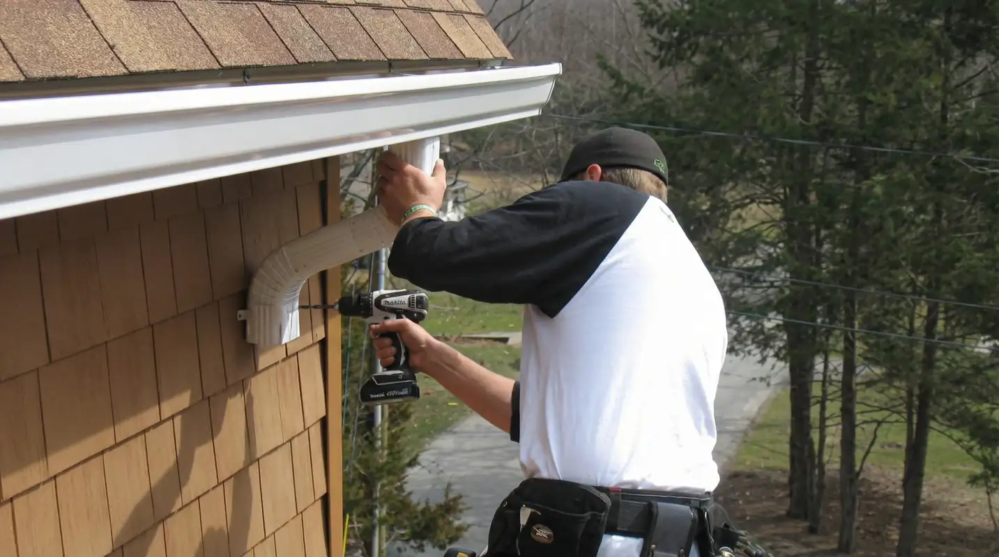 Professional contractor installing tan vinyl siding panels on a residential home exterior in Bloomington, IN